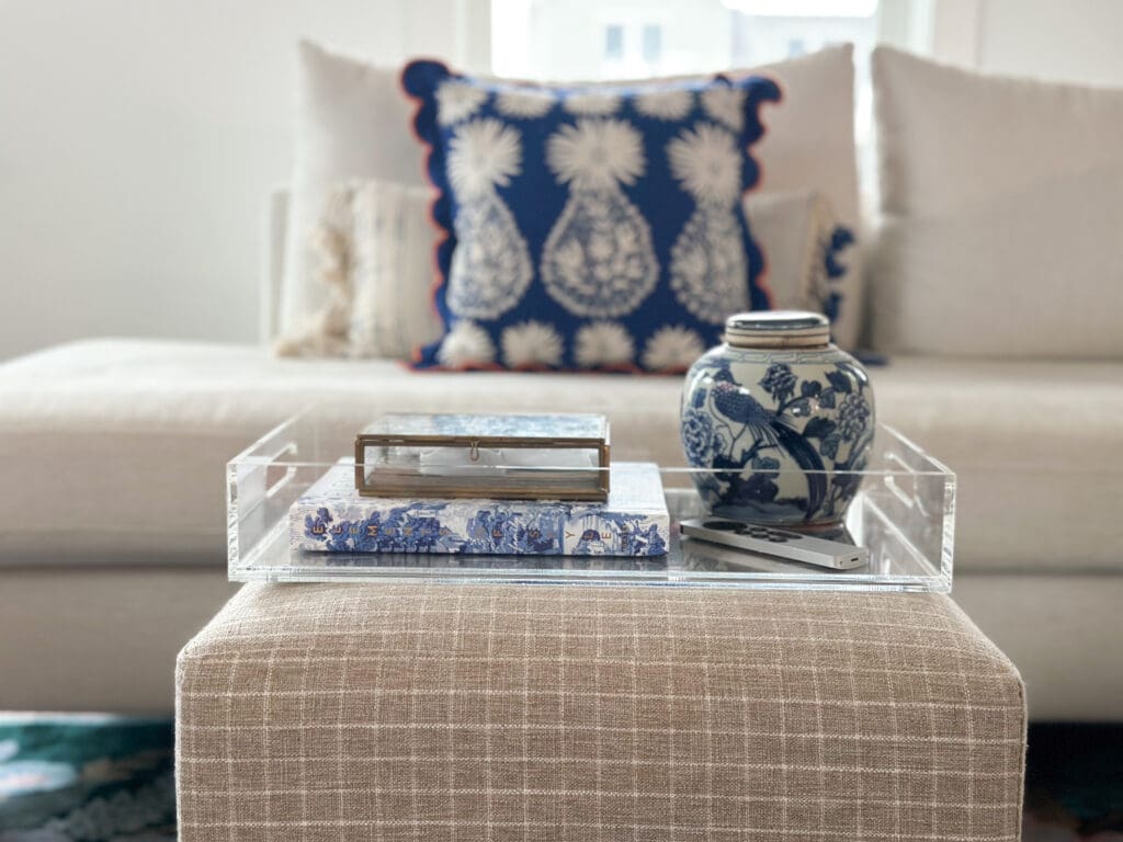 Acrylic tray atop ottoman beautifully styled in blues and whites