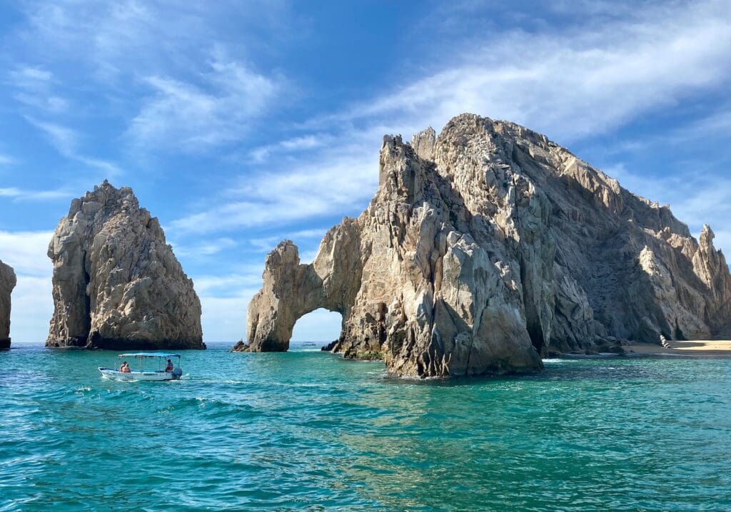Rock formation with small motorboat floating in front of it in Cabo 