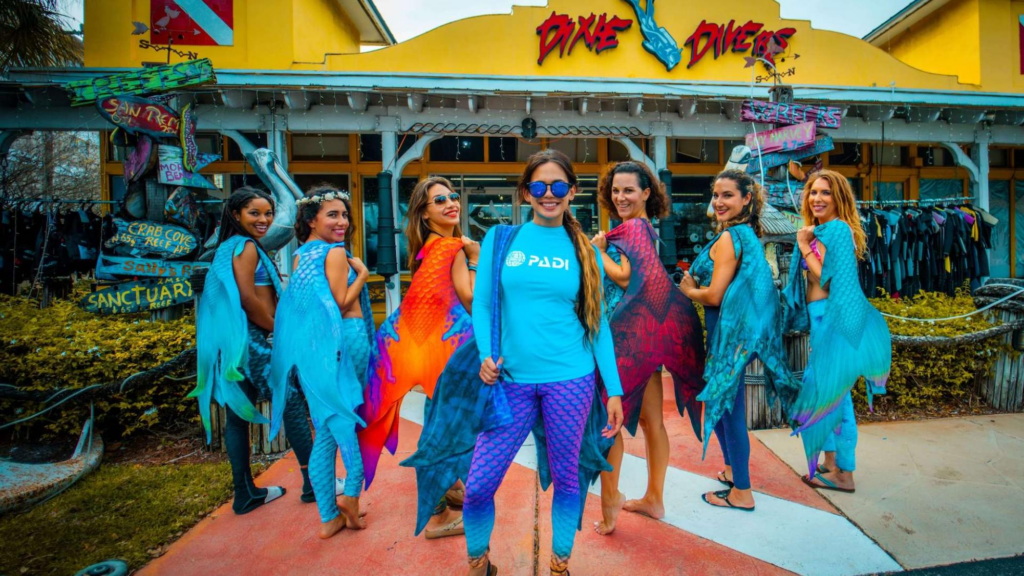 group of women holding mer tails and wearing PADI shirt