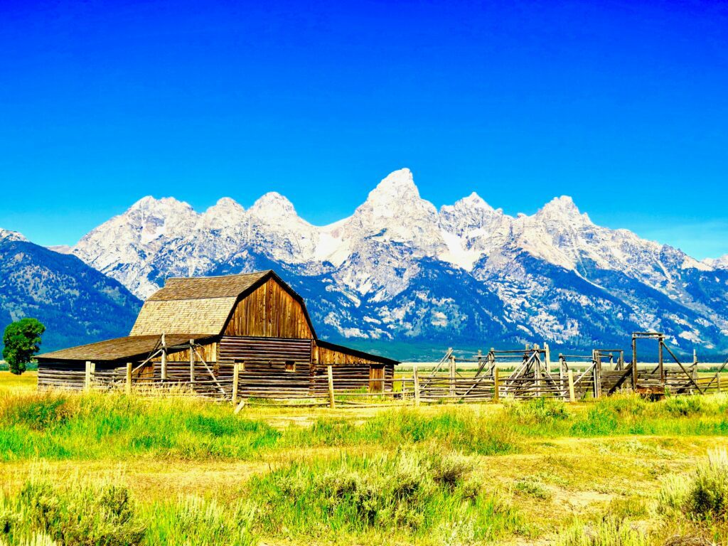 Dude ranches in Wyoming: snow-capped Tetons in background of rustic barn