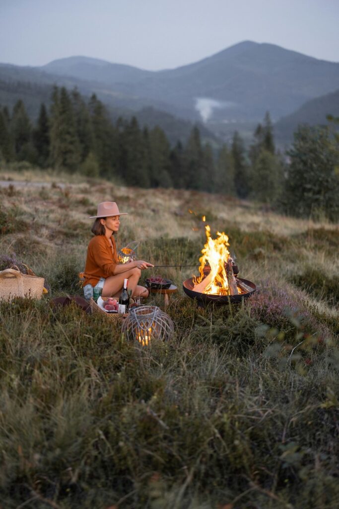 Dude ranches in Wyoming: Woman by campfire solo with mountains in background