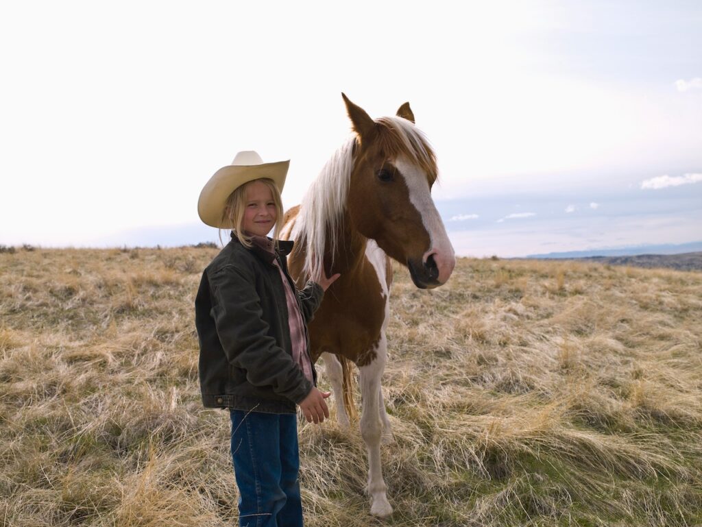 Young girl in cowboy hat with horse